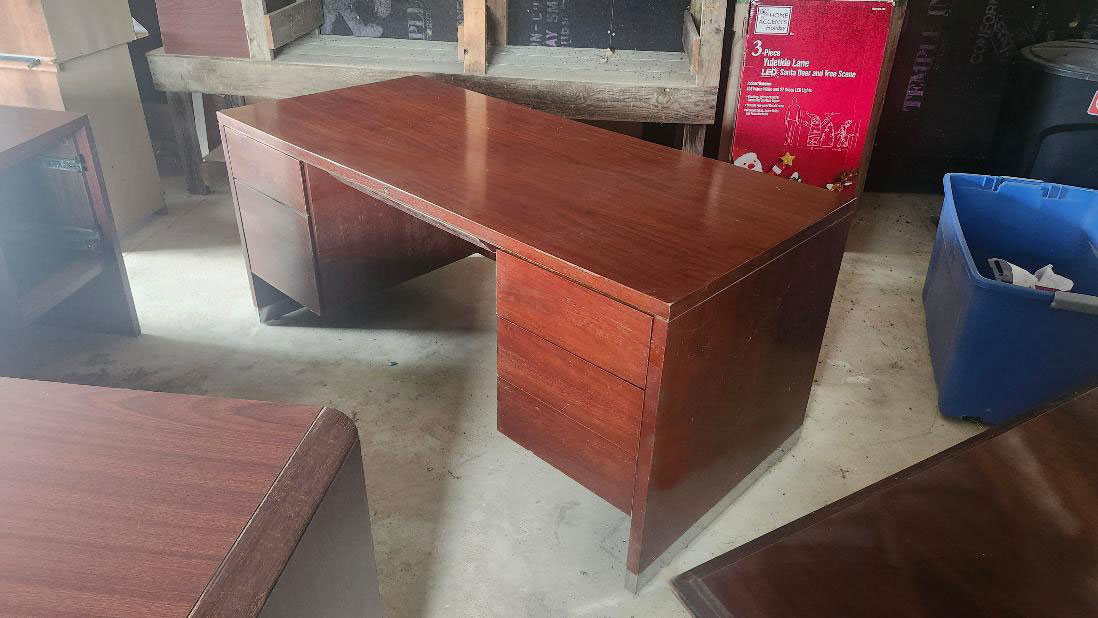Medium wooden desk with metal drawers in storage